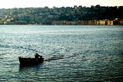 Man sailing on sea against sky in city