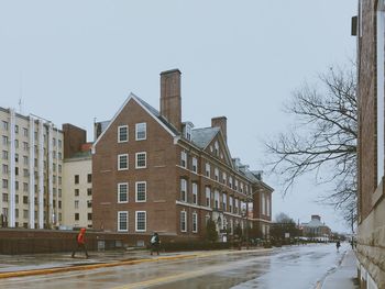 Road by buildings in city against clear sky