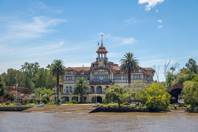 Built structures by river against sky