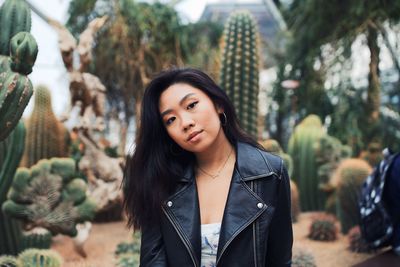 Portrait of young woman standing against plants