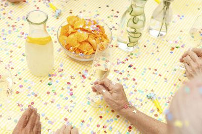 Celebrating senior sitting at table with infused water, champagne and potato chips