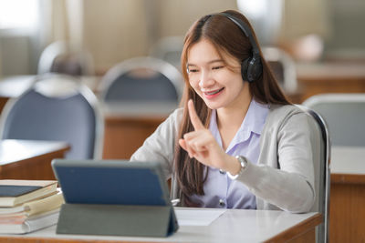 Smiling woman talking on video call while sitting at classroom