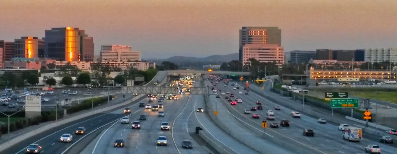 transportation, city, car, high angle view, mode of transport, land vehicle, architecture, building exterior, road, built structure, traffic, street, on the move, city life, road marking, cityscape, city street, travel, illuminated, sky