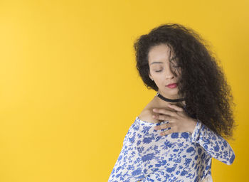 Portrait of a serious young woman over yellow background