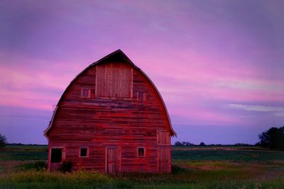 Barn on field against cloudy sky