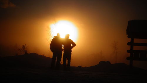 Silhouette man standing on field against sky during sunset