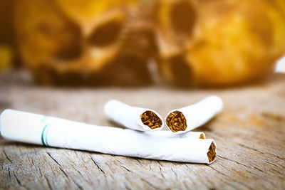 Close-up of cigarettes with human skulls on wooden table