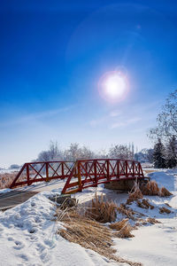 Bridge over snow covered land against sky