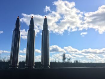 Close-up of bullets on railing against sky