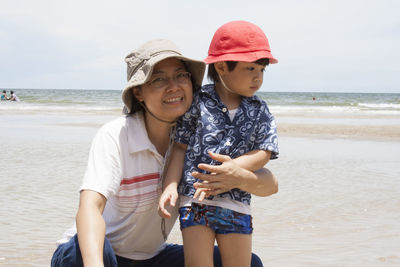 Smiling happy mother holding boy at beach