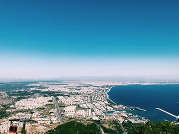 High angle view of townscape by sea against blue sky