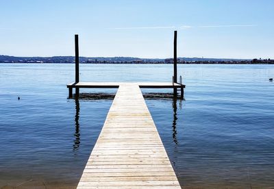 Wooden jetty on pier over lake against sky