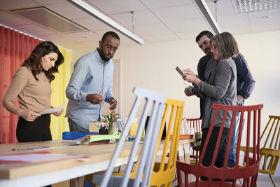 Multi-ethnic male and female engineers standing at table while working on project in office