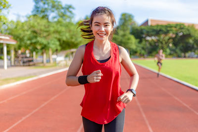 Portrait of smiling young woman with arms raised