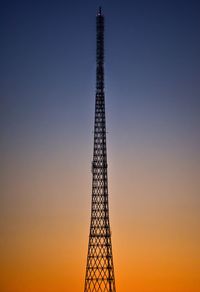 Low angle view of electricity pylon against sky during sunset