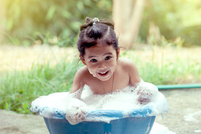 Portrait of happy girl taking bath in backyard