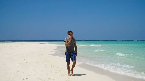 Man with a cell phone on the beach.