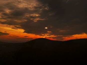 Scenic view of silhouette mountain against dramatic sky during sunset