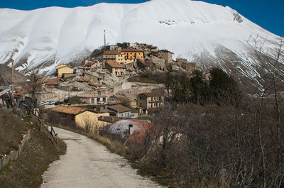 Snow covered houses by buildings in city