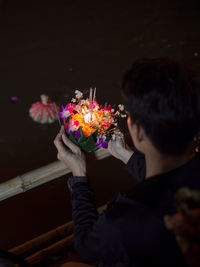 Close-up of man holding illuminated flower bouquet at event