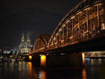 Illuminated bridge over river at night