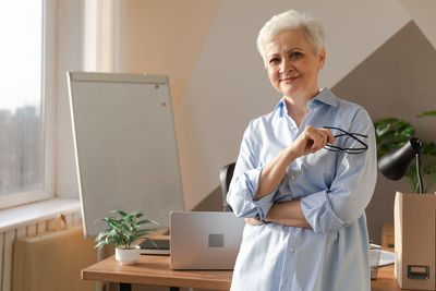 Portrait of female doctor using mobile phone while standing in office