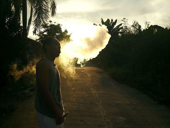 Man standing by tree against sky during sunset