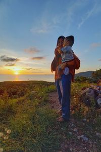 Man and son standing on land against sky during sunset