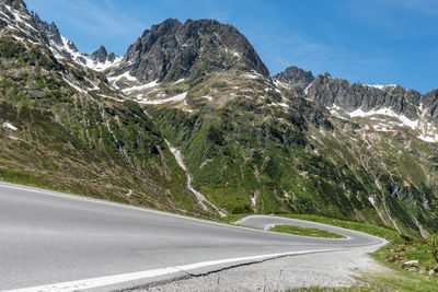 Road by mountains against sky