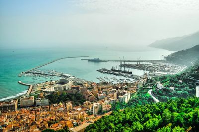 High angle view of city by sea against sky