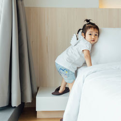 Portrait of girl climbing on bed