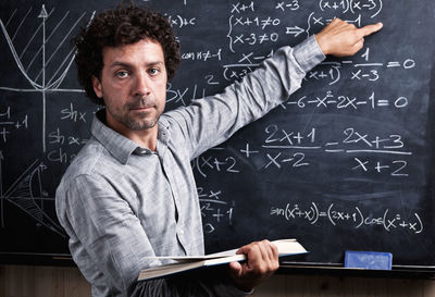 Portrait of teacher pointing on blackboard