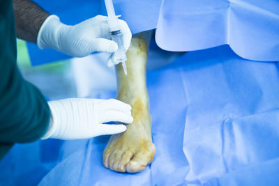 Cropped hands of doctor injecting patient at hospital