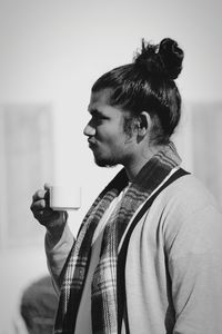 Side view of young man drinking coffee outdoors
