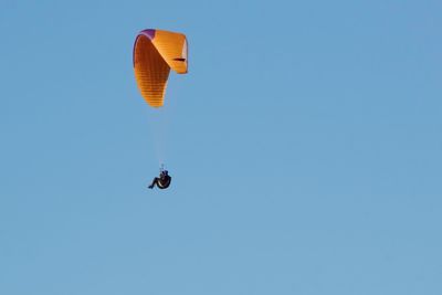 Low angle view of person paragliding against clear blue sky