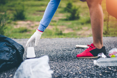 Low section of woman collecting garbage on road