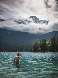 Rear view of shirtless man standing in lake