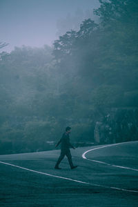 Man standing on road amidst trees