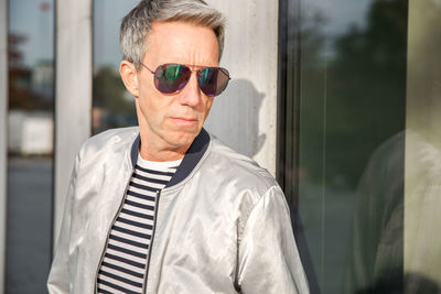 Man wearing sunglasses standing against wall