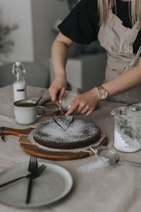 Woman cutting freshly baked chocolate cake