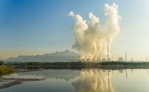 Smoke emitting from factory against sky