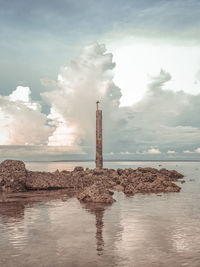 Driftwood on rocks by sea against sky