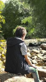 Rear view of woman sitting on rock