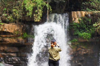 Rear view of man standing against waterfall