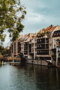 Buildings by river against sky