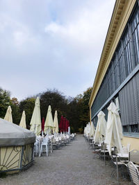 Empty chairs and tables against sky