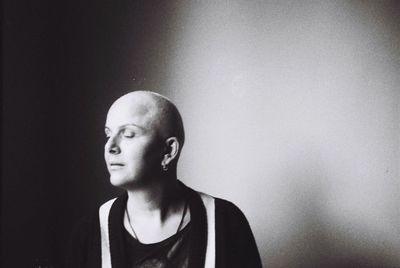 Mature woman with shaved head against wall