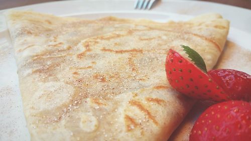 Close-up of fresh pancake and strawberries served in plate