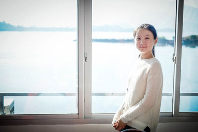 Portrait of young woman looking through window