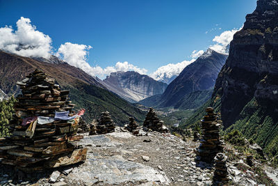 Stack of rocks on snowcapped mountains against sky